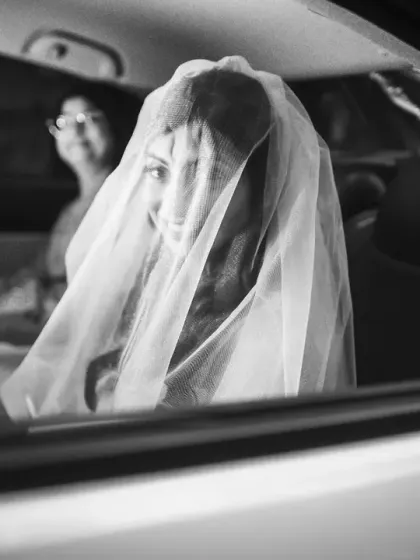 A black and white photo of the bride looking out of the car window, a classic and timeless bridal moment.