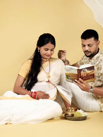The couple is captured reading together in their beautiful white and gold South Indian outfits. This studio setup is designed to be peaceful and culturally significant.