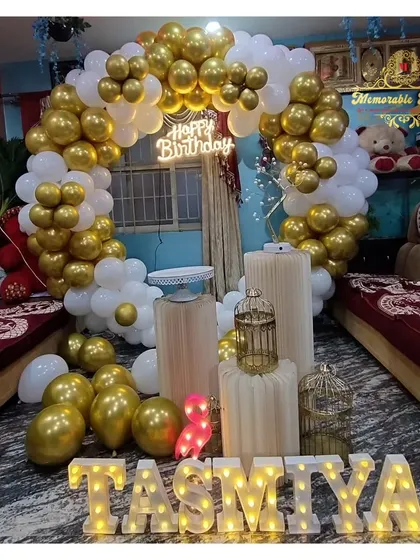 A classic white and gold balloon arch setup for a home birthday party.