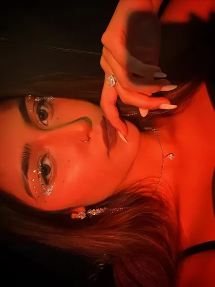A dramatic, high-fashion shot of a client with a heavy silver glitter eye look under red lighting.