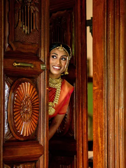 The bride peeking through a traditional wooden door, a beautiful candid moment before her grand entrance.
