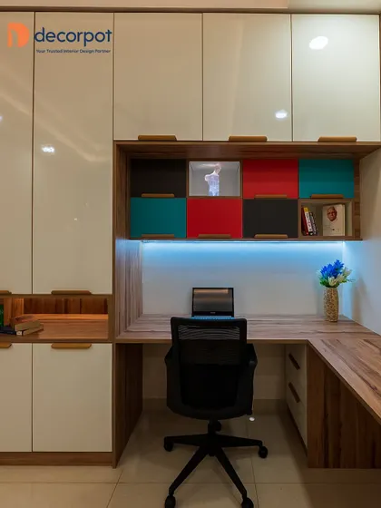 A productive workspace starts with smart design. This L-shaped study table is integrated with ample overhead and side storage, featuring a mix of closed cabinets and colorful open shelves for a personalized and organized home office.