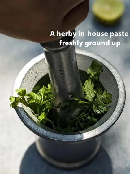 Grinding our coriander pesto by hand in a mortar and pestle. This traditional method helps release the essential oils and flavours of the fresh herbs.