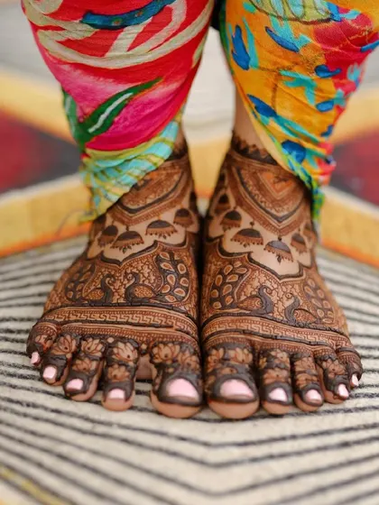 A professional photograph of the bride's feet, featuring a lovely peacock and doli design.