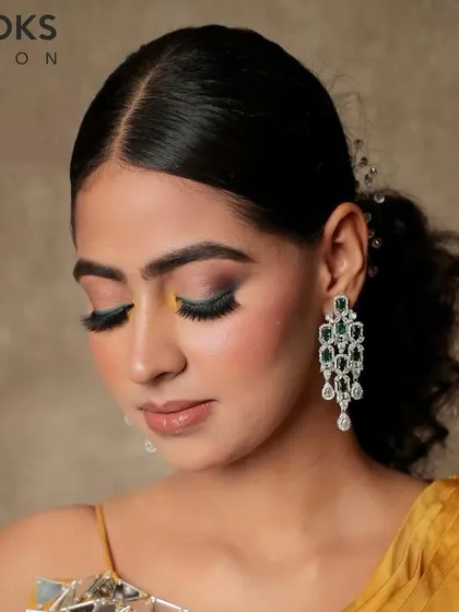 A softer take on a colorful party look. This image shows the blended teal and yellow eyeshadow with eyes closed, highlighting the seamless application and artistry of our makeup team.