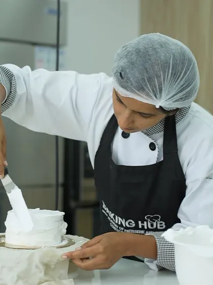 A student applying the final smooth coat of frosting. Mastering this skill is essential for a flawless finish, whether the cake is being left as is or covered in fondant.
