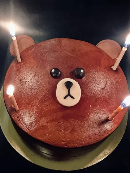 A simple but adorable bear face cake, lit with birthday candles.