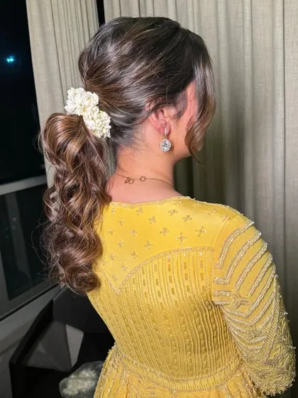 A detailed shot of the beautiful braided ponytail, adorned with fresh flowers. It's a perfect hairstyle for a festive occasion.