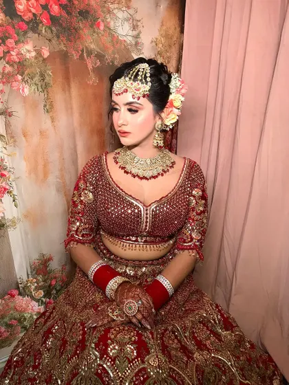 A full shot of the bride seated, her lehenga spread out beautifully around her.