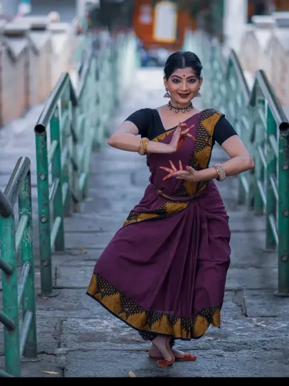 A graceful pose captured during a photoshoot at a temple. The setting provides a serene and powerful backdrop that complements the traditional aesthetics of Bharatanatyam.