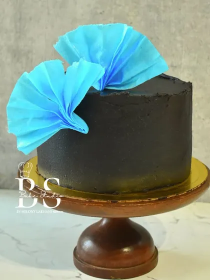 A sleek and modern ganache cake with a vibrant blue wafer paper fan, created by a student in my masterclass.