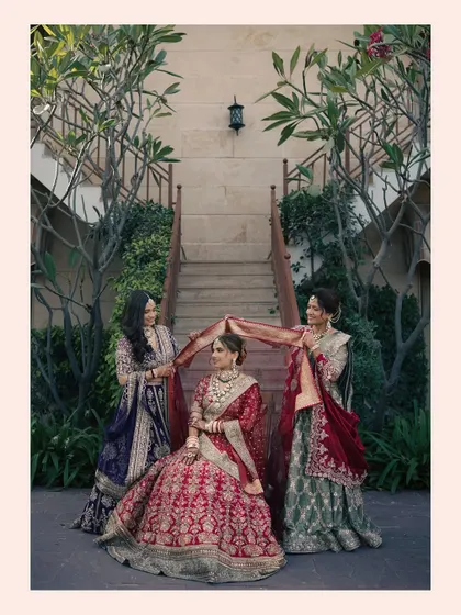 A heartwarming moment as the bride is surrounded by her bridesmaids, who hold her veil, creating a beautiful portrait of friendship and support.