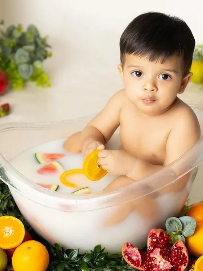 A healthy and fun fruit bath! This little one is surrounded by a colorful array of fresh fruits like oranges and watermelon, making for a unique and vibrant summer-themed shoot.