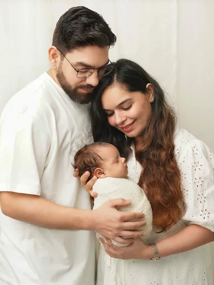 A family portrait where the parents are looking down at their newborn with adoration. This pose naturally creates a story of love and focus on the new baby.