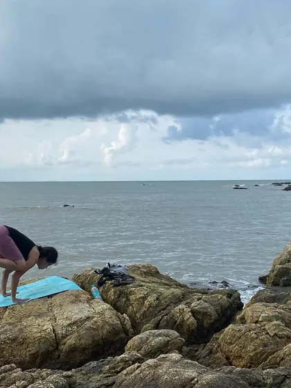 A student practices Bakasana (Crow Pose) on the rocks by the sea. This demonstrates the focus, balance, and adventurous spirit that we encourage in our community.