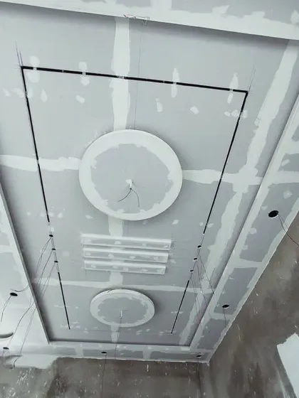 A modern ceiling layout with circular and rectangular elements, seen here before the final plastering. The black lines are guides for installing profile lights.
