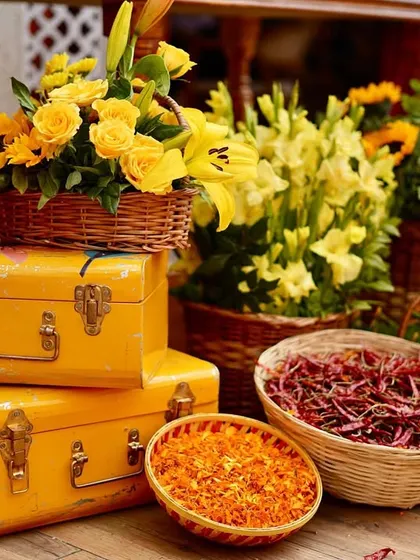 A vibrant corner that screams Rajasthan. We paired vintage yellow trunks with baskets of fresh marigolds, sunflowers, and even dried red chillies to create a rustic and colorful display.