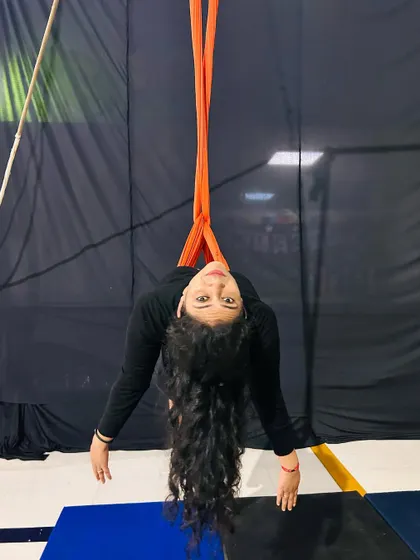 Looking at the camera from an inverted pose, this student shows the fun and unique perspective that comes with aerial arts.