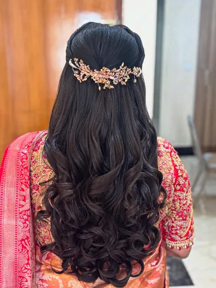 A romantic half-up hairstyle with voluminous, well defined curls. The look is completed with an elegant, leaf motif hair accessory that adds a touch of sparkle without overpowering the style.