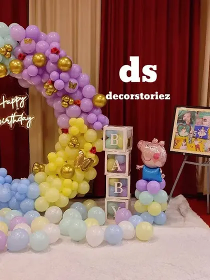 A wide view of a pastel Peppa Pig first birthday in a banquet hall. The setup includes a balloon ring, 'BABY' blocks, a photo display easel, and return gift bags, showing how I can manage the entire event space.