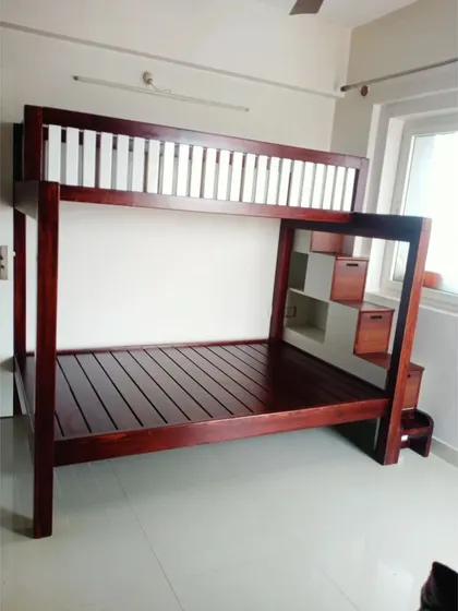 A classic solid wood bunk bed, perfect for a kids' room. This design features a sturdy frame, safety railings on the top bunk, and an integrated staircase with built-in drawers for storing toys and clothes.