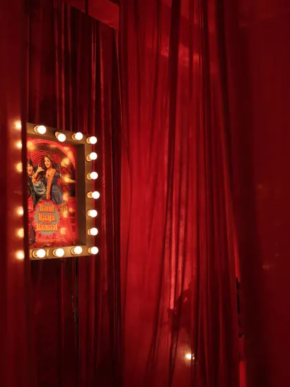 A personalized movie poster of the couple, framed with vanity lights and set against a wall of red velvet, adding to the old-Bollywood charm.