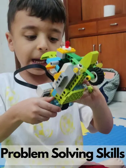 A student proudly holds his hopping robot, a fun project that teaches mechanics and programming.