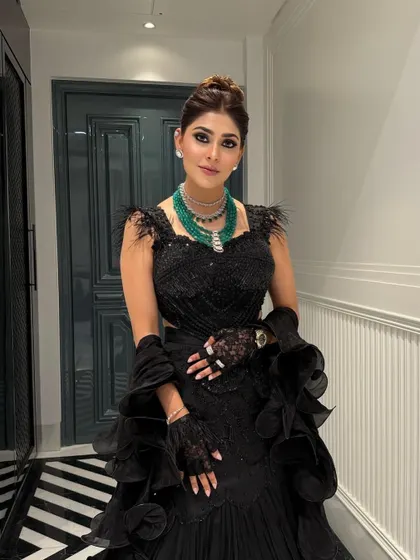 This high bun complements the dramatic silhouette of the black gown, creating a powerful and chic look for a formal evening event or reception party.
