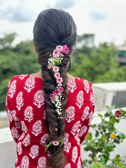 A beautiful fishtail braid adorned with a delicate trail of pink and white flowers, creating a whimsical and romantic look.
