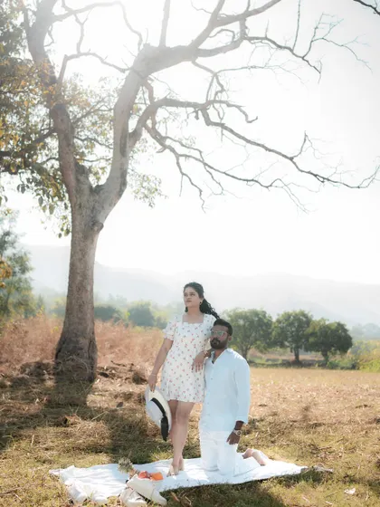 A couple poses in a wide, open field with mountains in the background. The expansive landscape adds a sense of freedom and adventure to their pre-wedding photos.