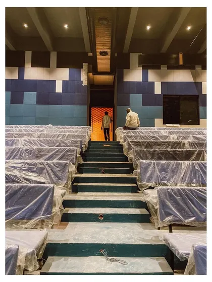 This is the auditorium of the memorial complex during its final stages of construction. The pixelated acoustic wall paneling in shades of blue adds visual interest and functional sound dampening to what is designed as a hub for community events.