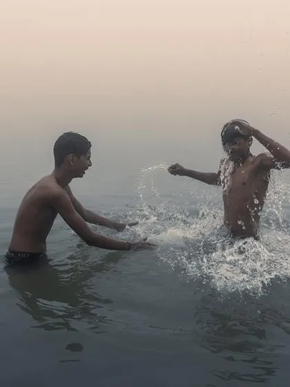 Two boys splash and play in the Ganga river in Bihar, their joy evident in this candid moment captured during the golden morning light.