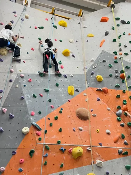 A wide view of our kids' climbing area, with several young climbers enjoying different routes simultaneously. There's always something new to try.