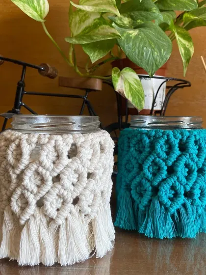 A clear shot of the macrame mason jar covers in both off-white and teal. The detailed knot pattern is visible, showing the quality of our craftsmanship.