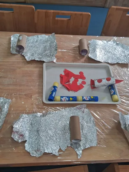 Our space exploration theme starts with hands-on creation. This is the setup for making foil-wrapped rockets, a craft that combines art with our science lesson on the solar system.