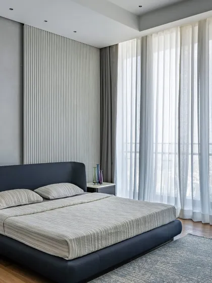 A minimalist bedroom with large windows that let in ample natural light. The simple color scheme and uncluttered design create a peaceful and airy retreat.