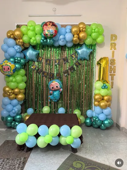 Another angle of the Cocomelon first birthday decoration. This view shows the full arrangement, including the cake table area framed by the colorful balloon arch.