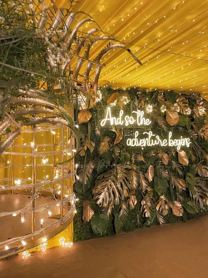 "And so the adventure begins." This fun neon sign against a wall of lush greenery and golden leaves was the perfect photo-op for a vibrant Mehendi and Sangeet night.