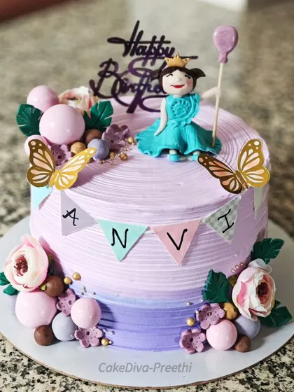 A super cute princess-themed cake for a birthday girl. This pineapple sponge cake is decorated with a lavender ombre, a fondant princess, butterflies, and a personalized name banner.