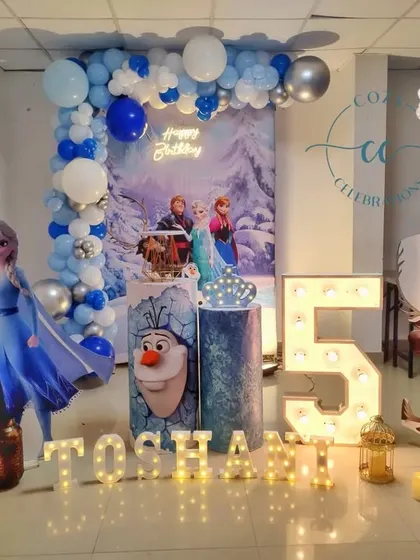 This Frozen party for a 5th birthday features cutouts of Elsa, Anna, Olaf, and Sven, creating a complete character scene.