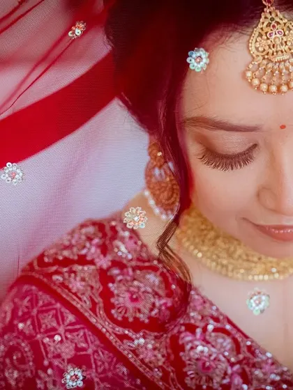 The color version of the previous portrait. The rich red of the veil and the gold of her jewelry come to life, creating a vibrant and traditional bridal image.