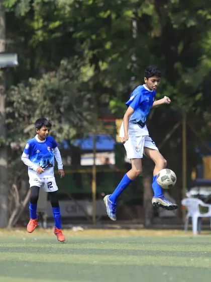 A player shows great technique, controlling the ball in mid-air during a U13 game.