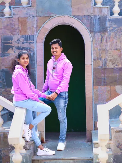 A casual and sweet photo of a couple in matching pink hoodies, posing on a rustic set.
