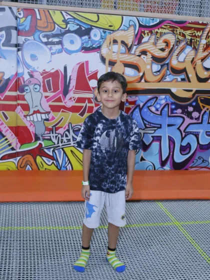 Standing in front of our vibrant graffiti wall, this young guest is ready to explore all the fun our trampoline park has to offer.
