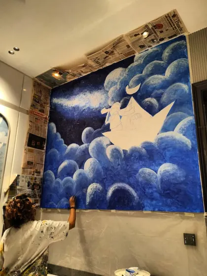 Painting the fluffy clouds in the night sky. I use different shades of blue and white to create depth and a soft, dreamy texture.