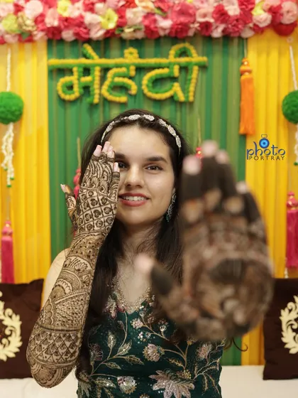 A playful shot of the bride peeking through her henna-covered hands during her Mehndi ceremony.
