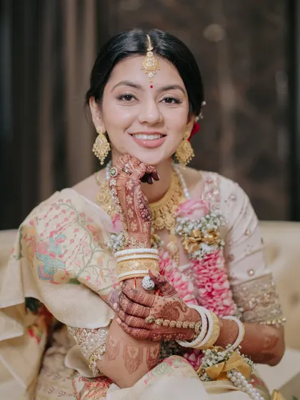 Posing with her intricate henna, this bride's smile is the centerpiece. Her clean makeup and traditional gold jewelry create a look of timeless grace.