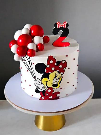 A sweet and simple Minnie Mouse cake for a second birthday. This design features a hand-painted Minnie holding a bunch of balloons, with a matching number '2' topper.