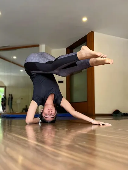 Exploring different leg positions from a stable headstand base. This helps improve proprioception and control.