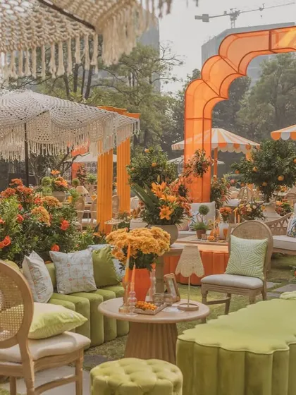 A comfortable lounge area at the 'Orange Orchard' Haldi, with a mix of green and orange velvet seating and custom-printed cushions.